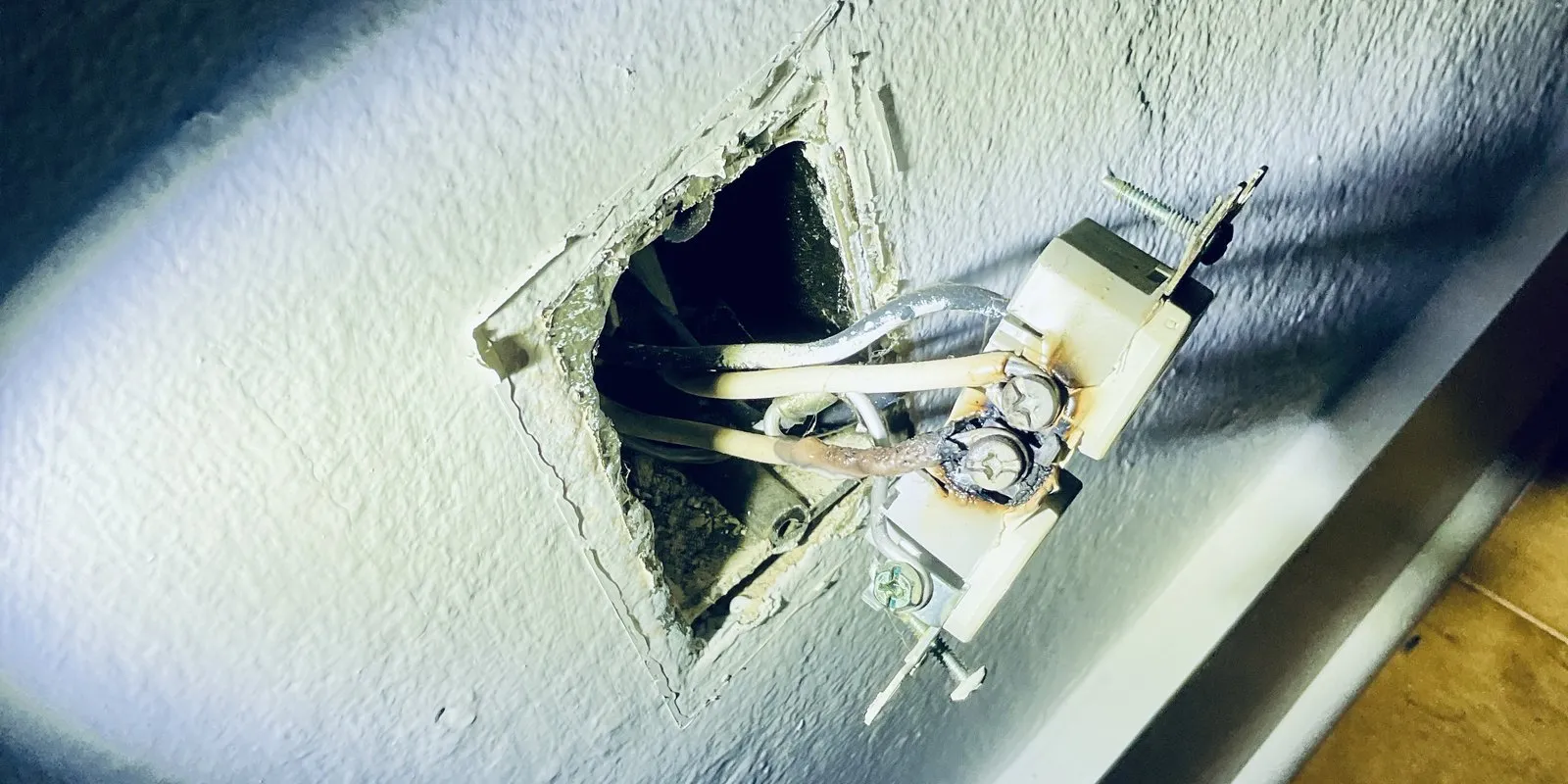 A charred, overheated outlet pulled from the wall — a failed connection that killed power to a room.