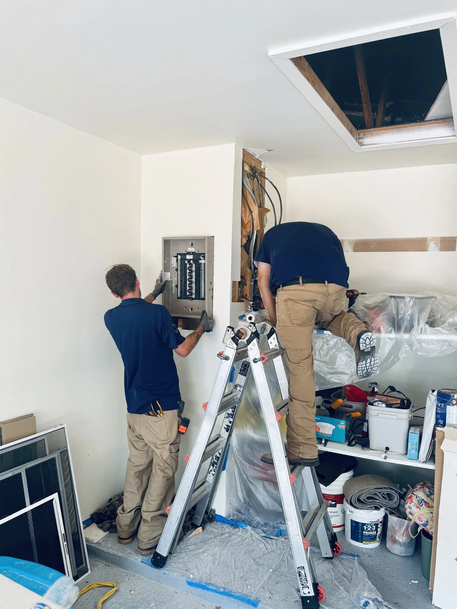 Two-technician indoor panel install in a garage — licensed residential electrician in Austin TX (DC Electric)